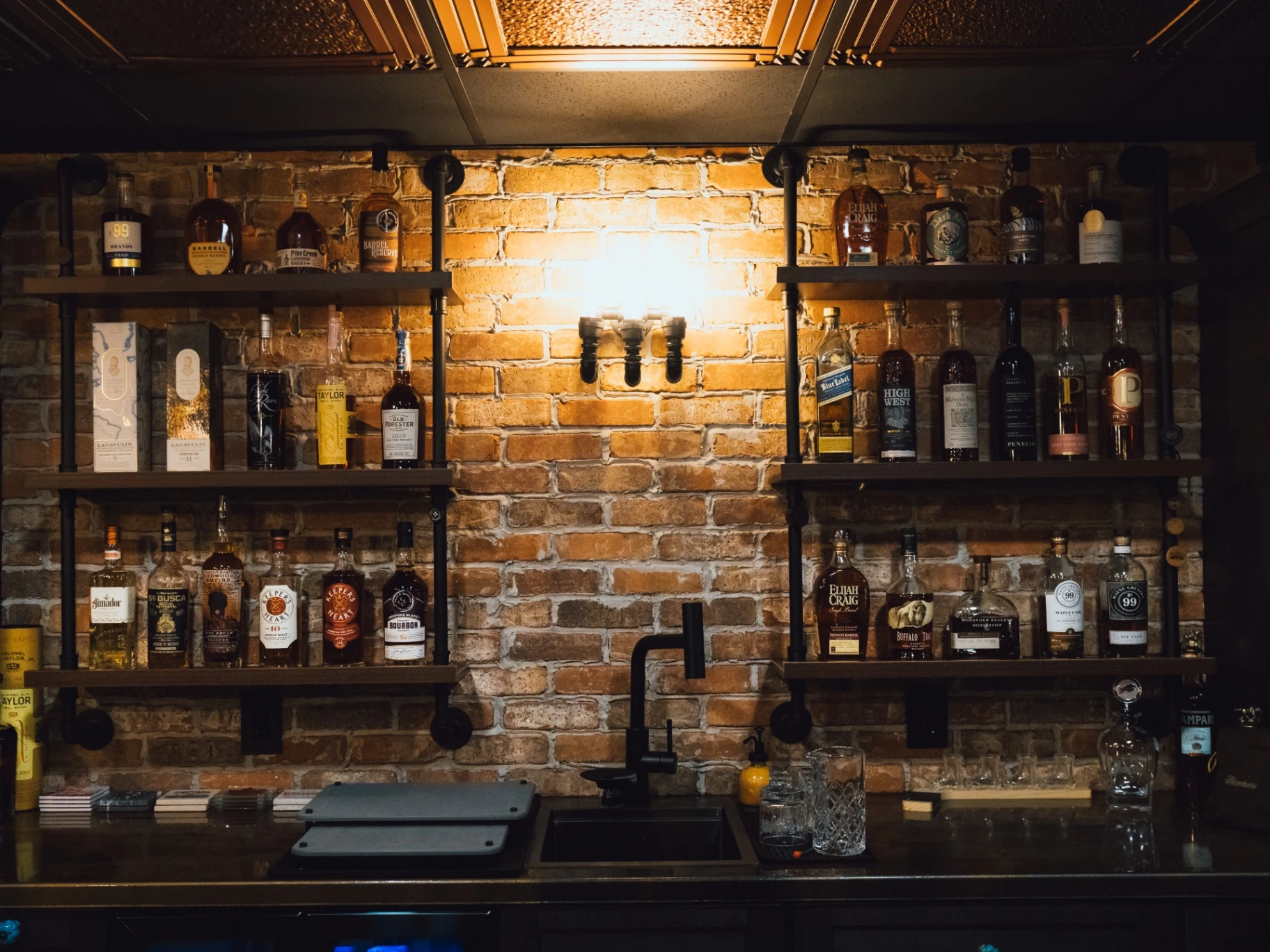 Close-up of the custom bar's brick wall, bottle shelving, sink, and lighting