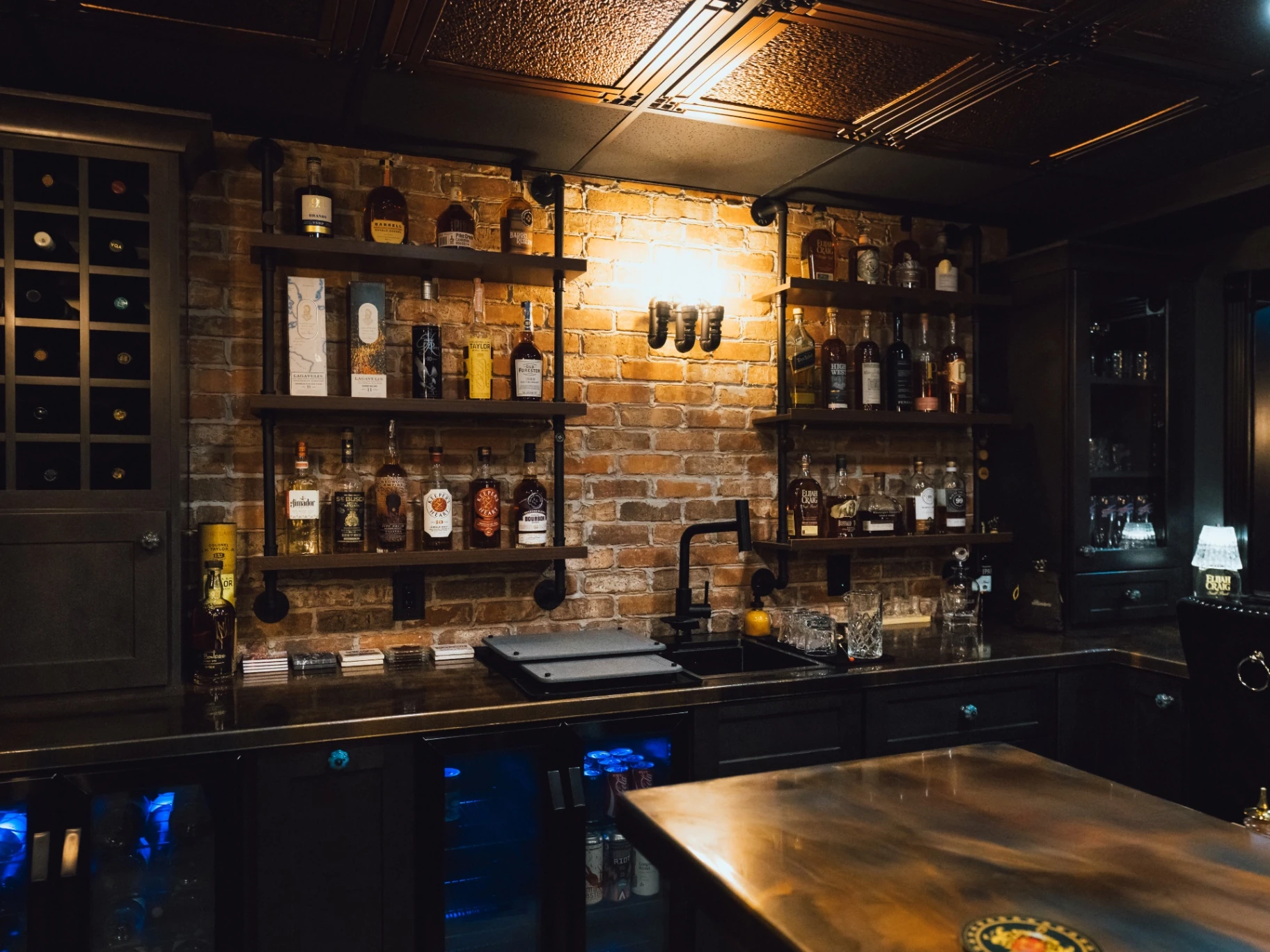 Wide view of the custom bar's brick backdrop, shelving, sink, and under-counter refrigerators