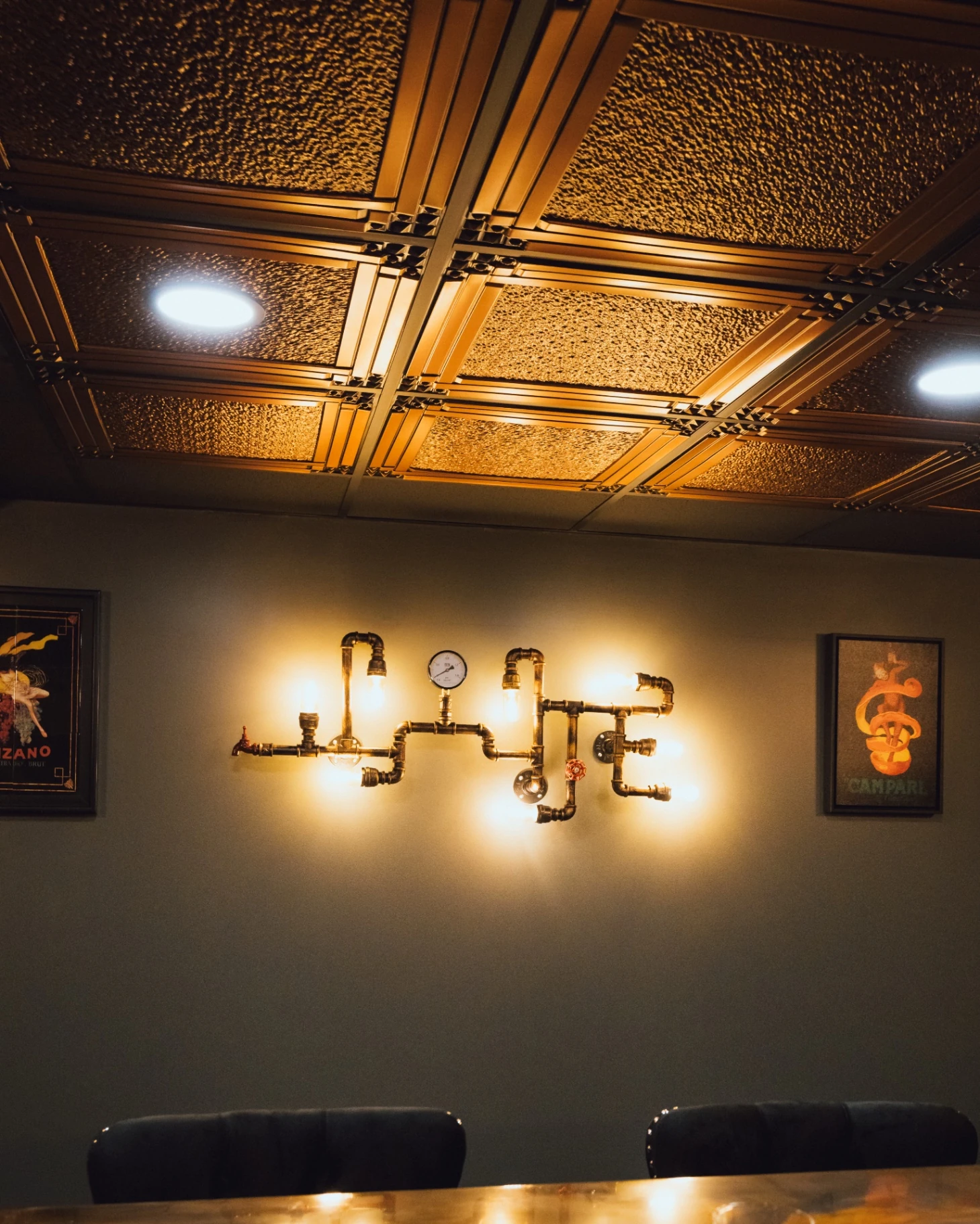 Detailed view of the custom bar's patterned ceiling and pipe-style wall lighting
